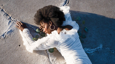 Lady wearing an alluring, high-quality white laced dress with loop earings.