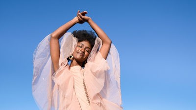 Woman model wearing a maxi laced dress in nude color by Studio 504. 